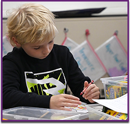 Elementary school boy coloring at his desk
